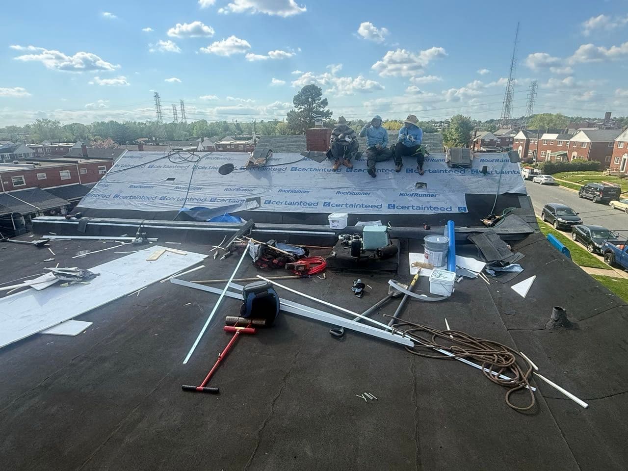 Apper Construction crew installing underlayment on a low-slope flat roof section in Maryland